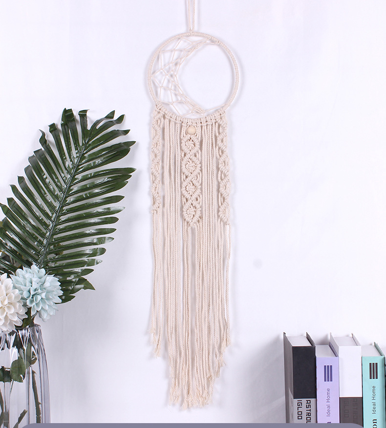 Boho cotton macramé wall tapestry with crescent moon design, hanging in a cozy room setting with books and plants, adding a relaxed, artistic touch to the space.