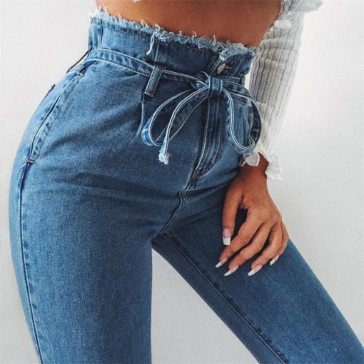 Woman wearing blue paperbag waist skinny jeans with a tie belt, showcasing a trendy mid-waist fit and stonewashed finish for a high-street look.
