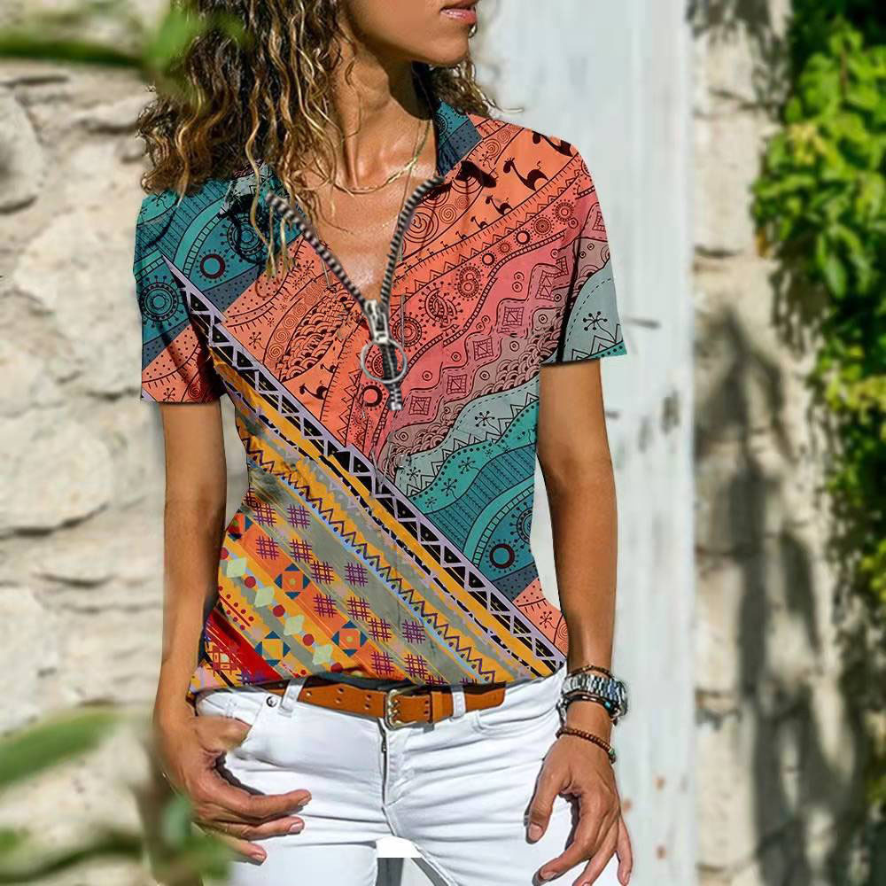 Woman wearing a colorful ethnic print short sleeve t-shirt with a relaxed fit, styled with white pants and a brown belt for a chic casual look.