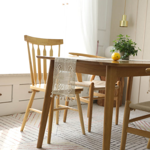 Vintage beige lace crochet table flag with tassel accents, draped over a wooden table, enhancing the cozy dining space.