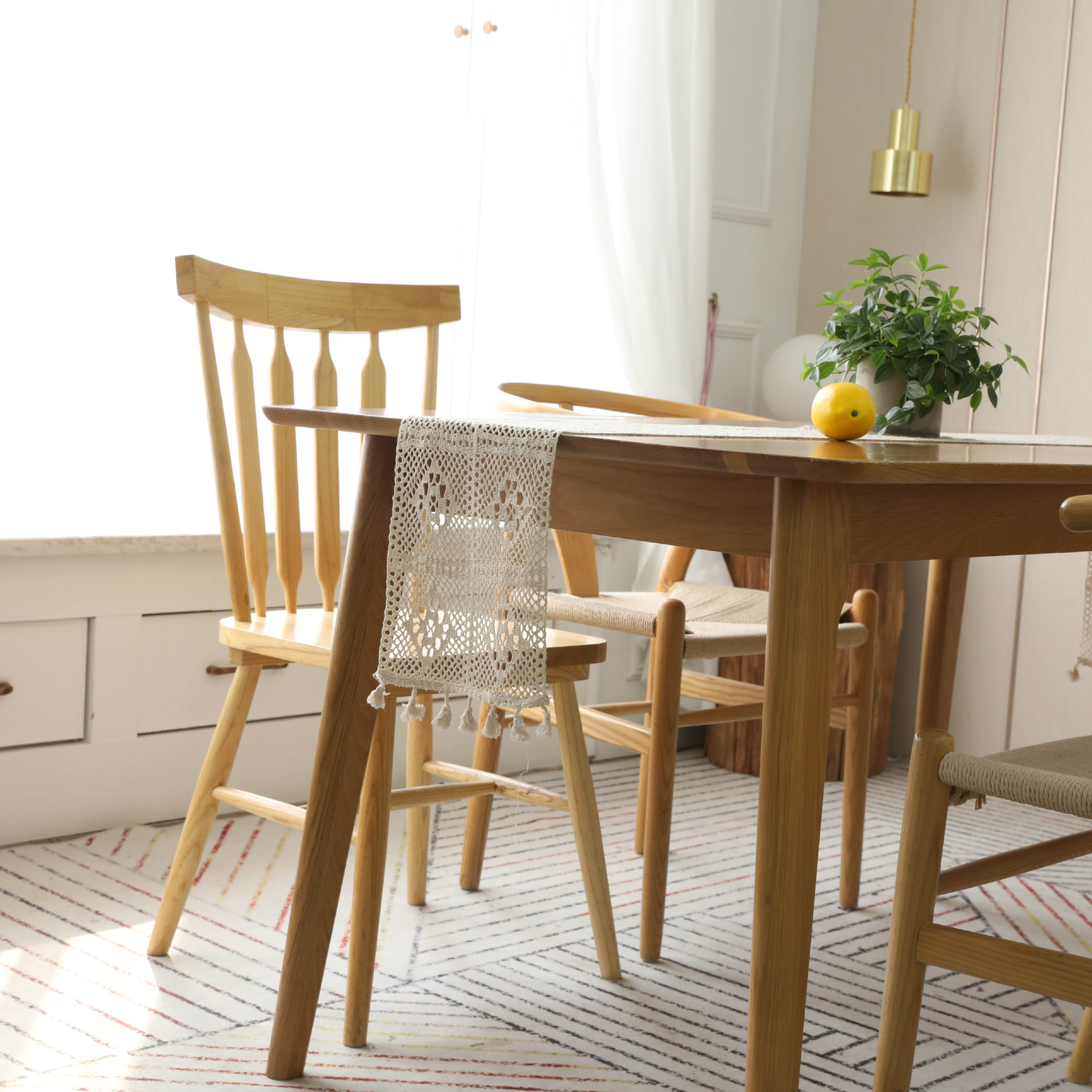 Vintage beige lace crochet table flag with tassel accents, draped over a wooden table, enhancing the cozy dining space.