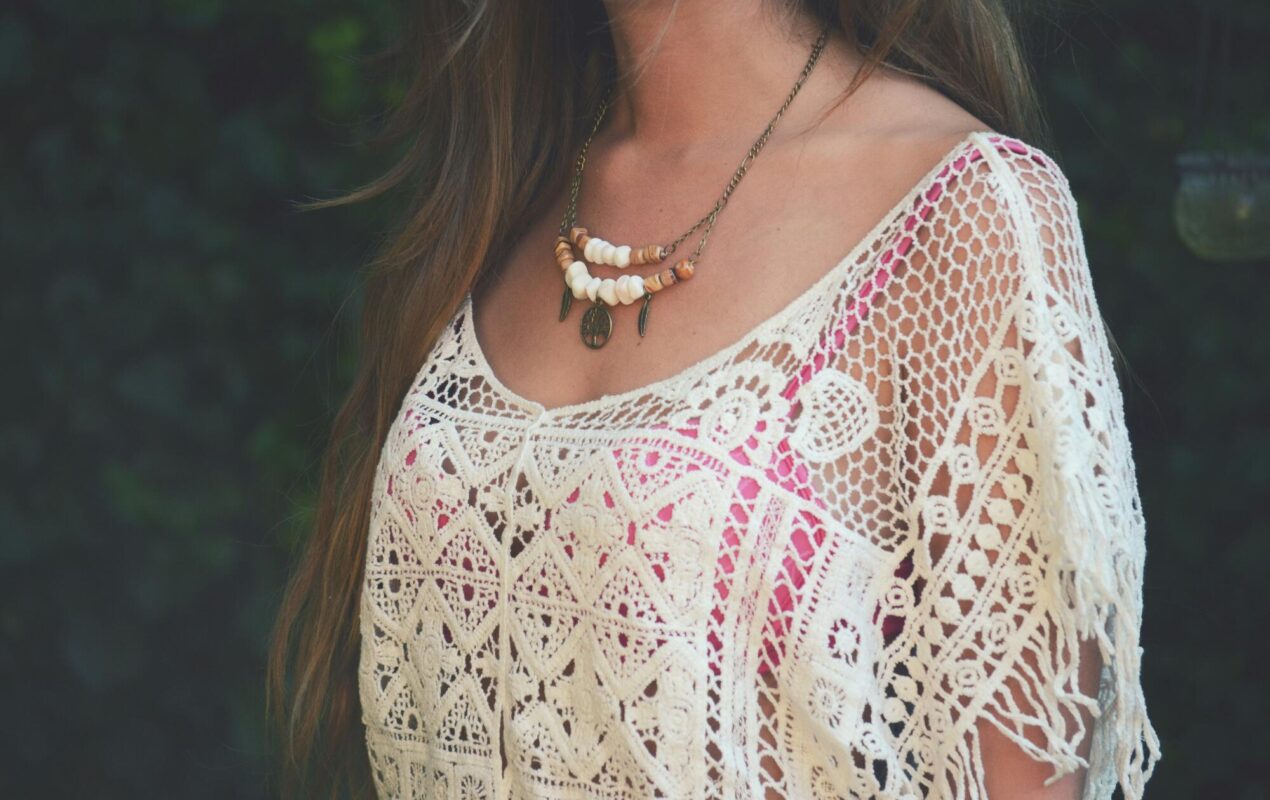 A woman in a white and red boho floral shirt wearing a silver necklace.